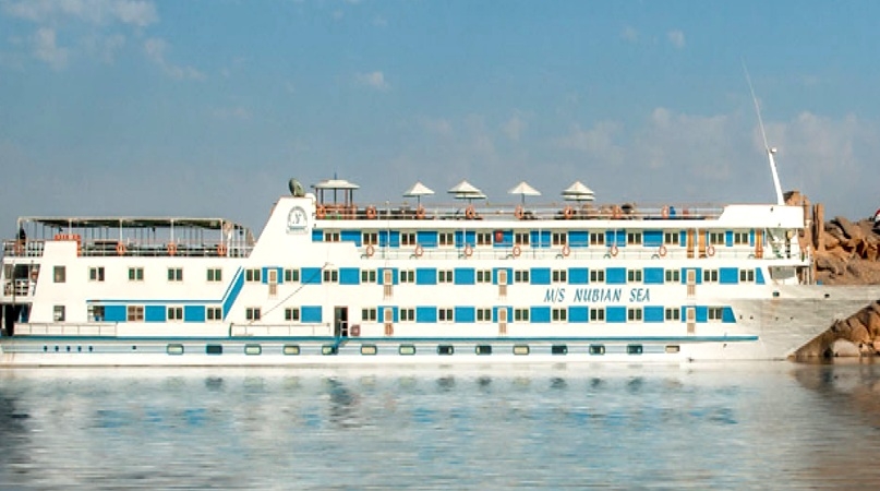 The MS Nubian Sea cruise ship sailing on calm waters with umbrellas on the top deck.