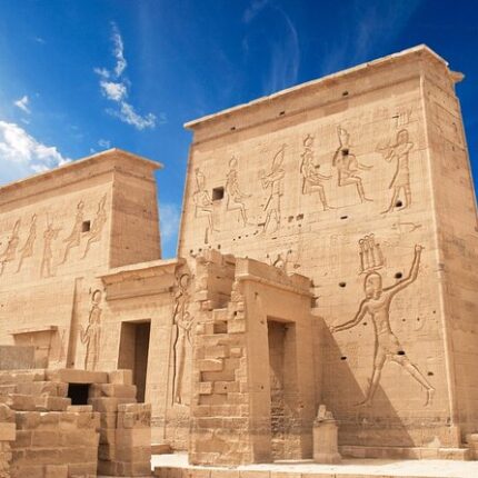 Ancient Egyptian temple with detailed hieroglyphic carvings on its walls under a clear blue sky.